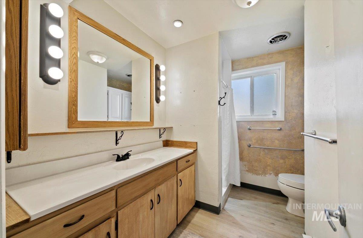 Full bathroom featuring vanity, light wood-style flooring, and a shower with shower curtain