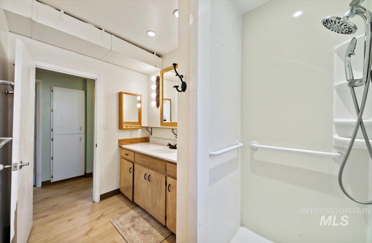 Bathroom with a walk in shower, vanity, light wood-style flooring, and recessed lighting