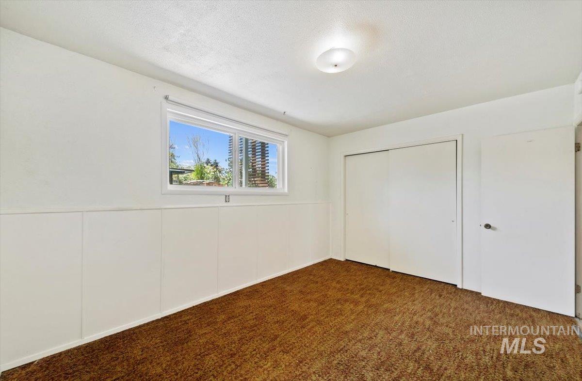 Unfurnished bedroom with dark colored carpet, a closet, and a textured ceiling