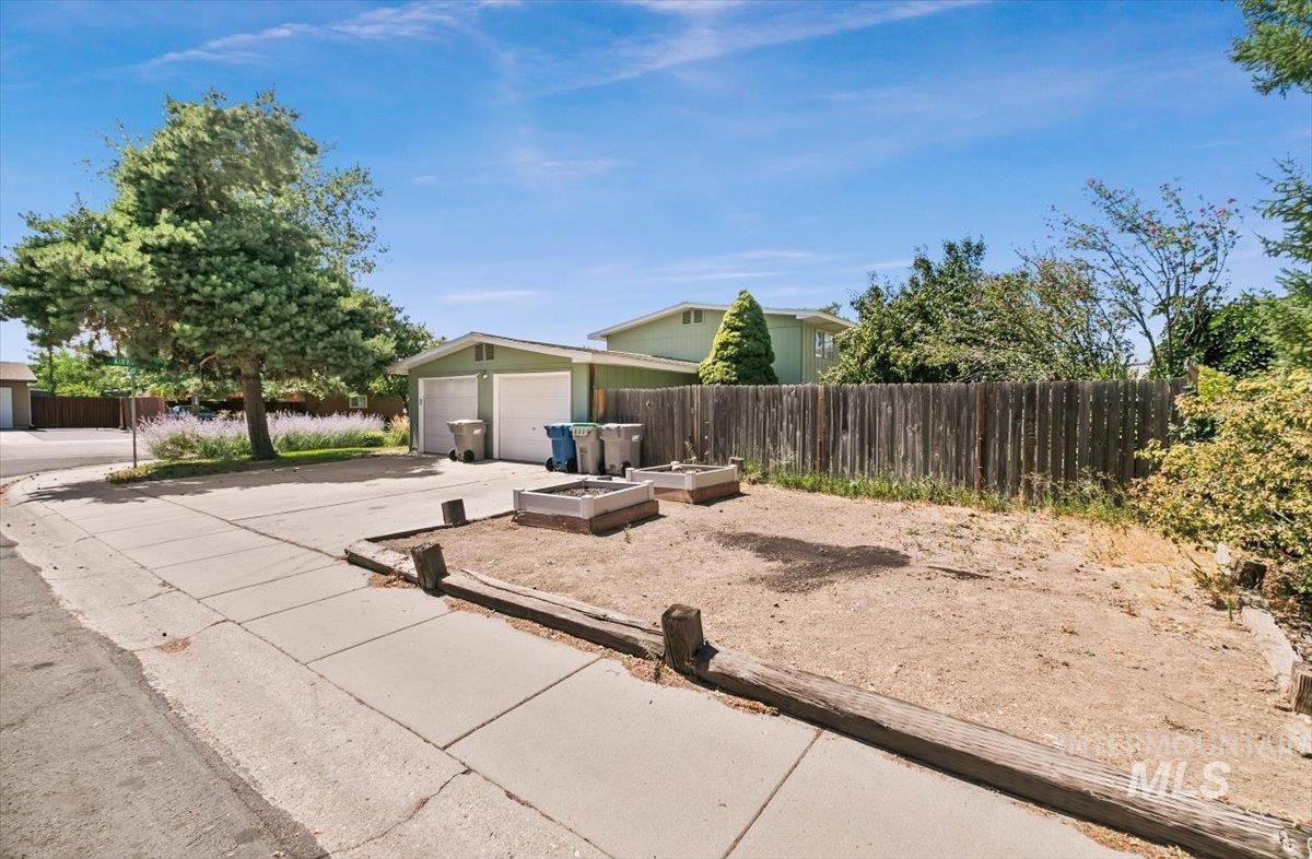 View of front of house featuring driveway, an outbuilding, and a garden