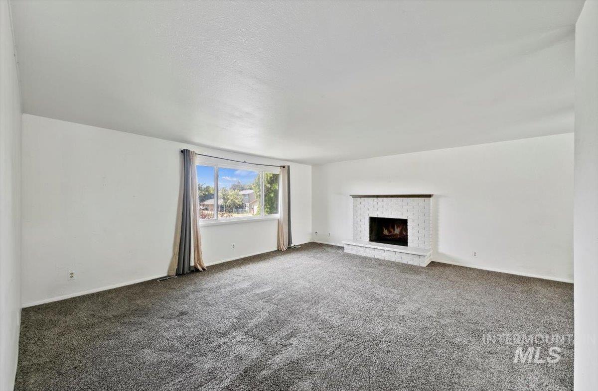 Unfurnished living room featuring carpet floors, a fireplace, and a textured ceiling