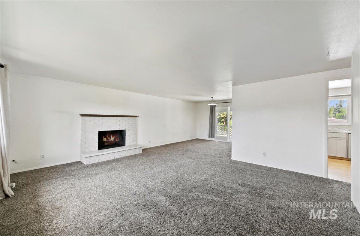 Unfurnished living room with carpet flooring and a fireplace