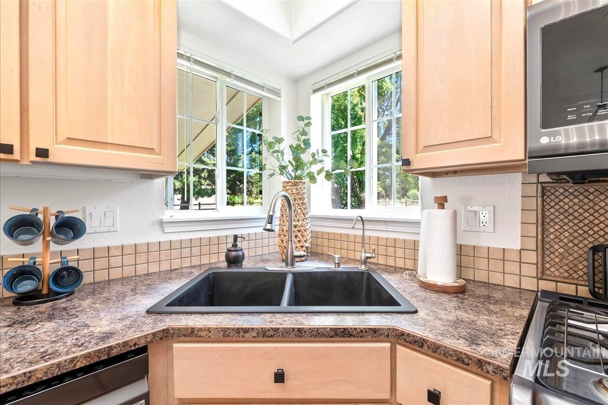 Kitchen with stainless steel appliances, light brown cabinetry, and tasteful backsplash