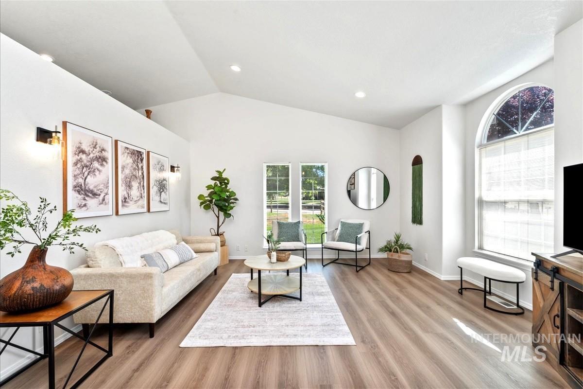 Living room with lofted ceiling, light wood-style floors, and recessed lighting