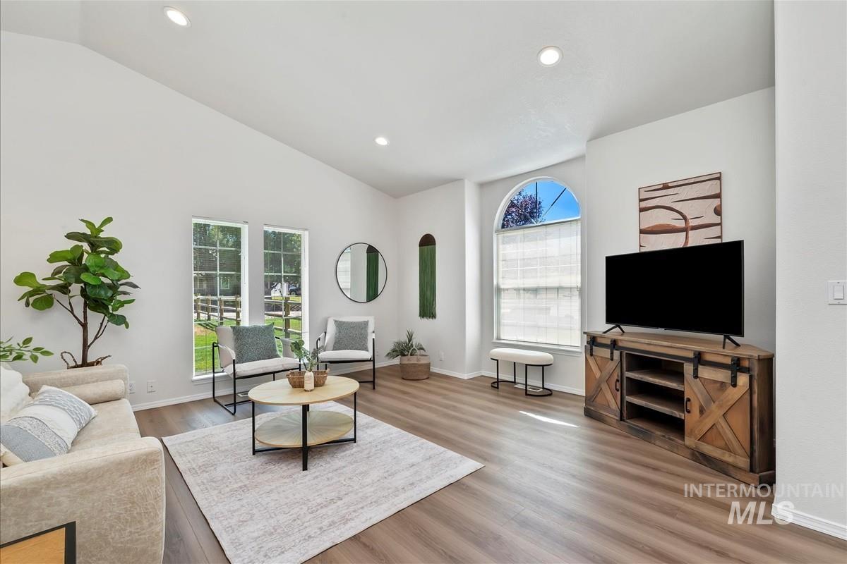 Living room with recessed lighting, light wood-style flooring, and lofted ceiling