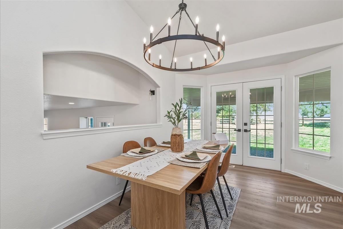 Dining space with french doors, dark wood finished floors, a chandelier, and lofted ceiling