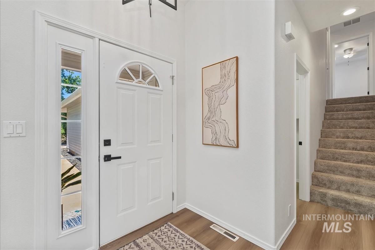 Foyer entrance featuring wood finished floors, stairway, and recessed lighting