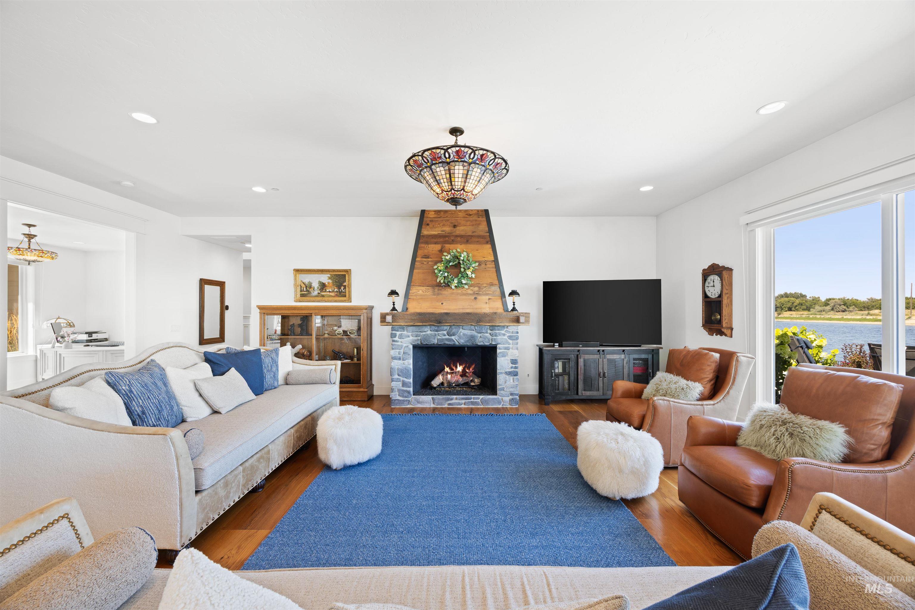 Living room featuring wood finished floors, a stone fireplace, and recessed lighting