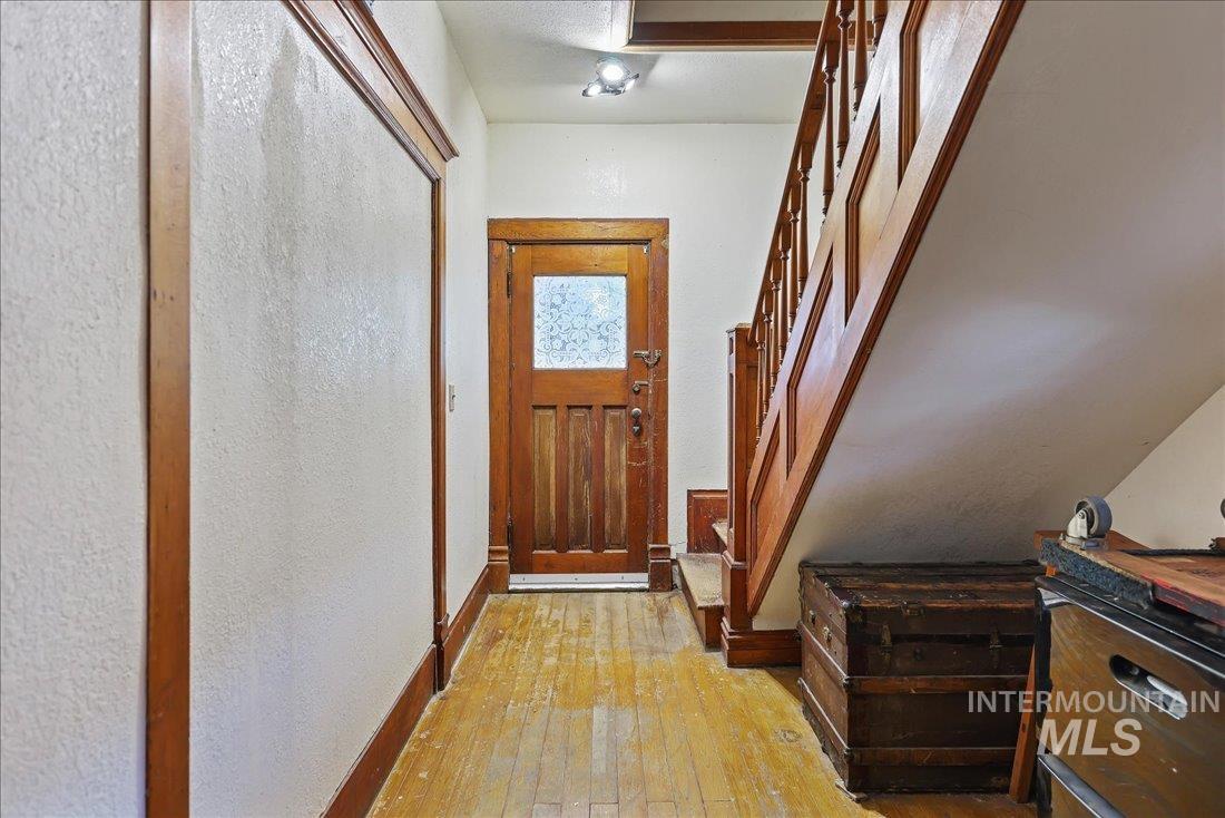 Doorway with hardwood / wood-style flooring, a textured wall, and stairway