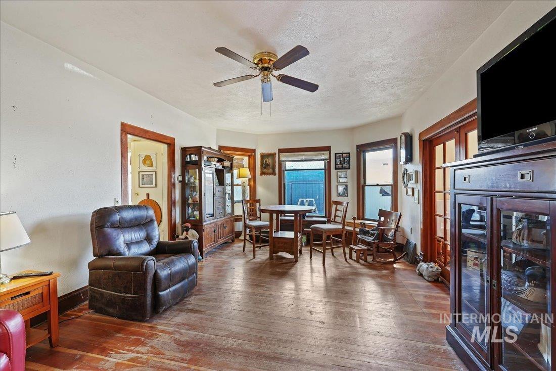Sitting room with dark wood-type flooring, a textured ceiling, and ceiling fan