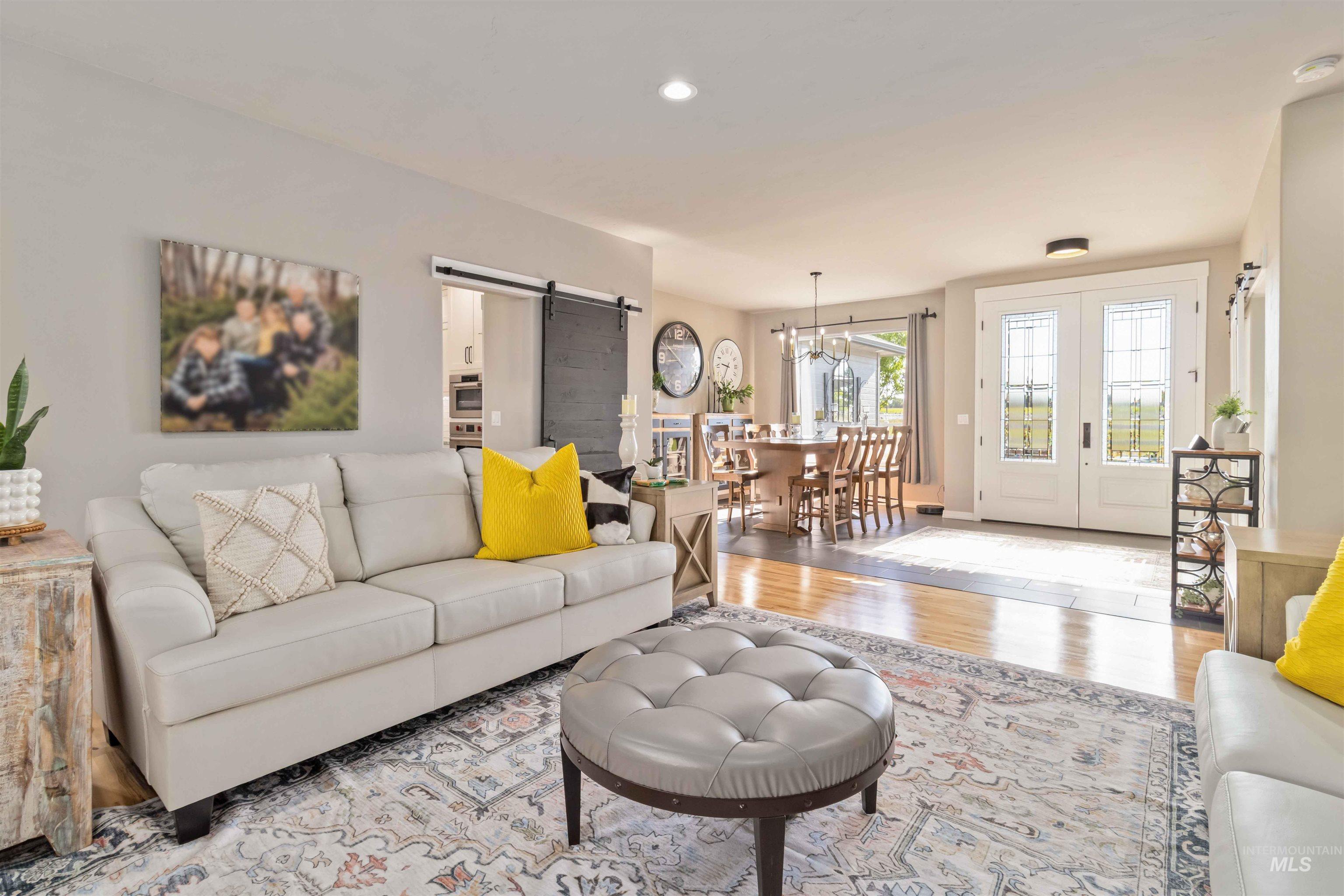 Living room with a barn door, wood finished floors, and recessed lighting