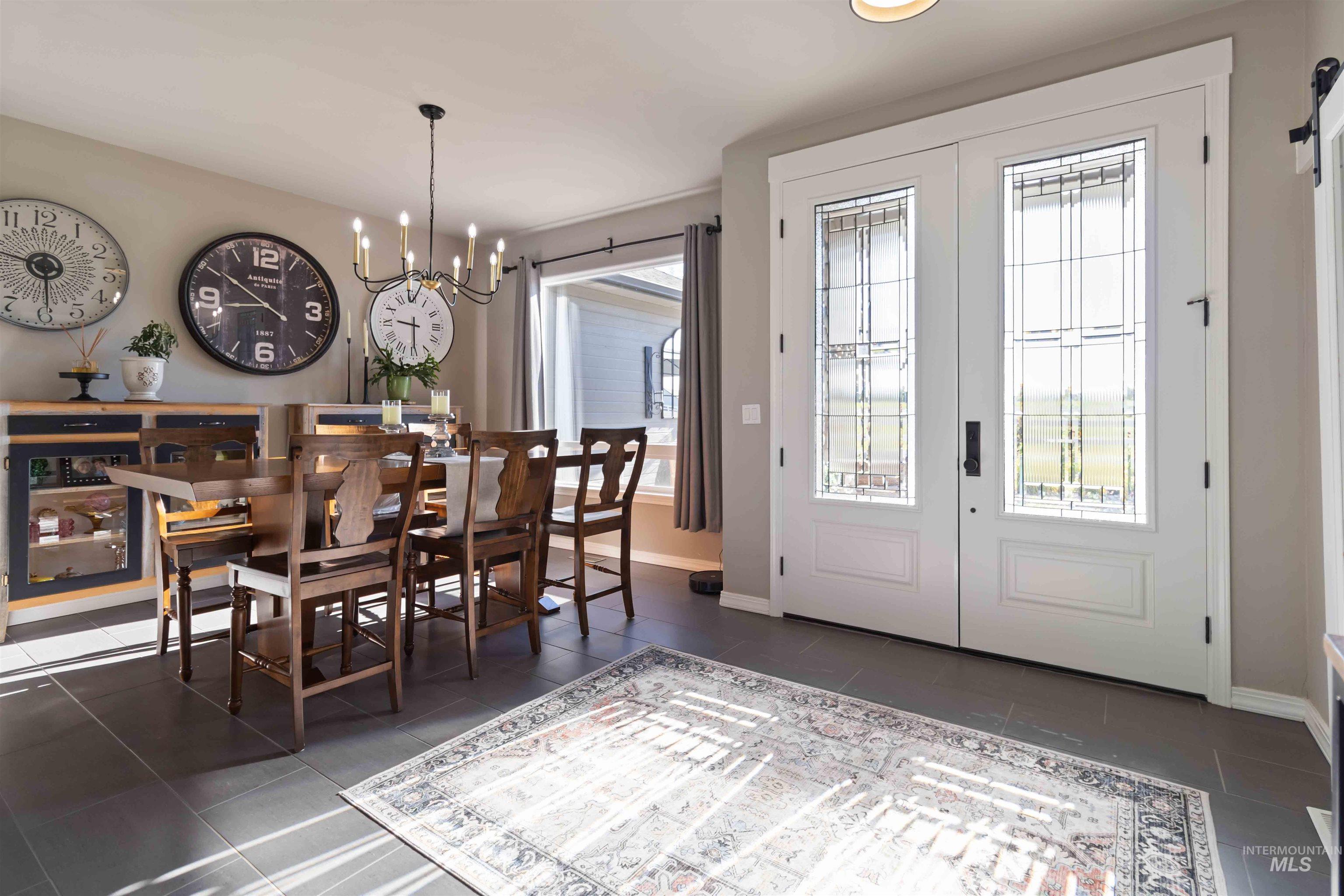 Dining space with healthy amount of natural light, a chandelier, french doors, and dark tile patterned floors