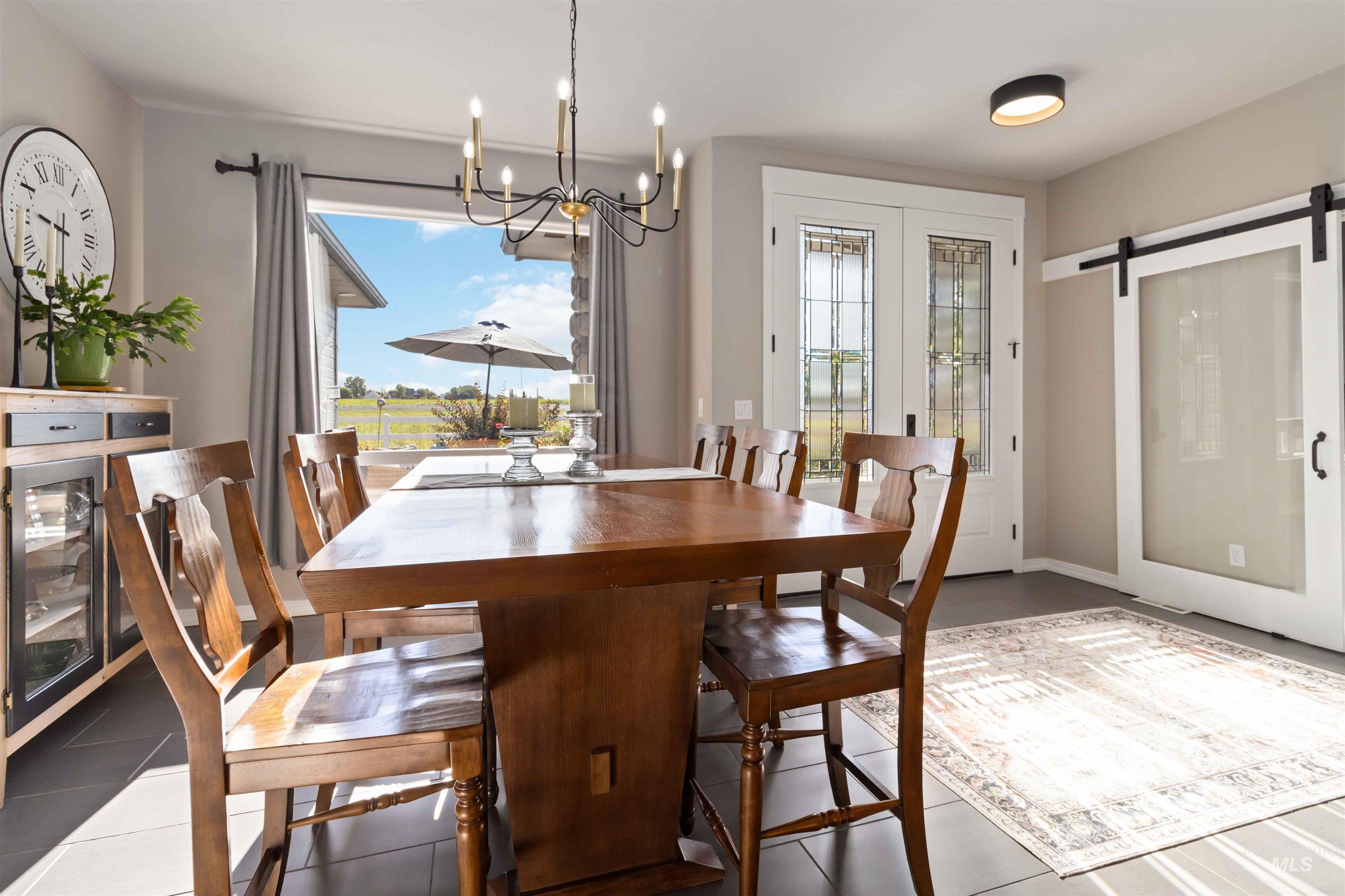 Tiled dining room featuring a barn door, healthy amount of natural light, and a chandelier