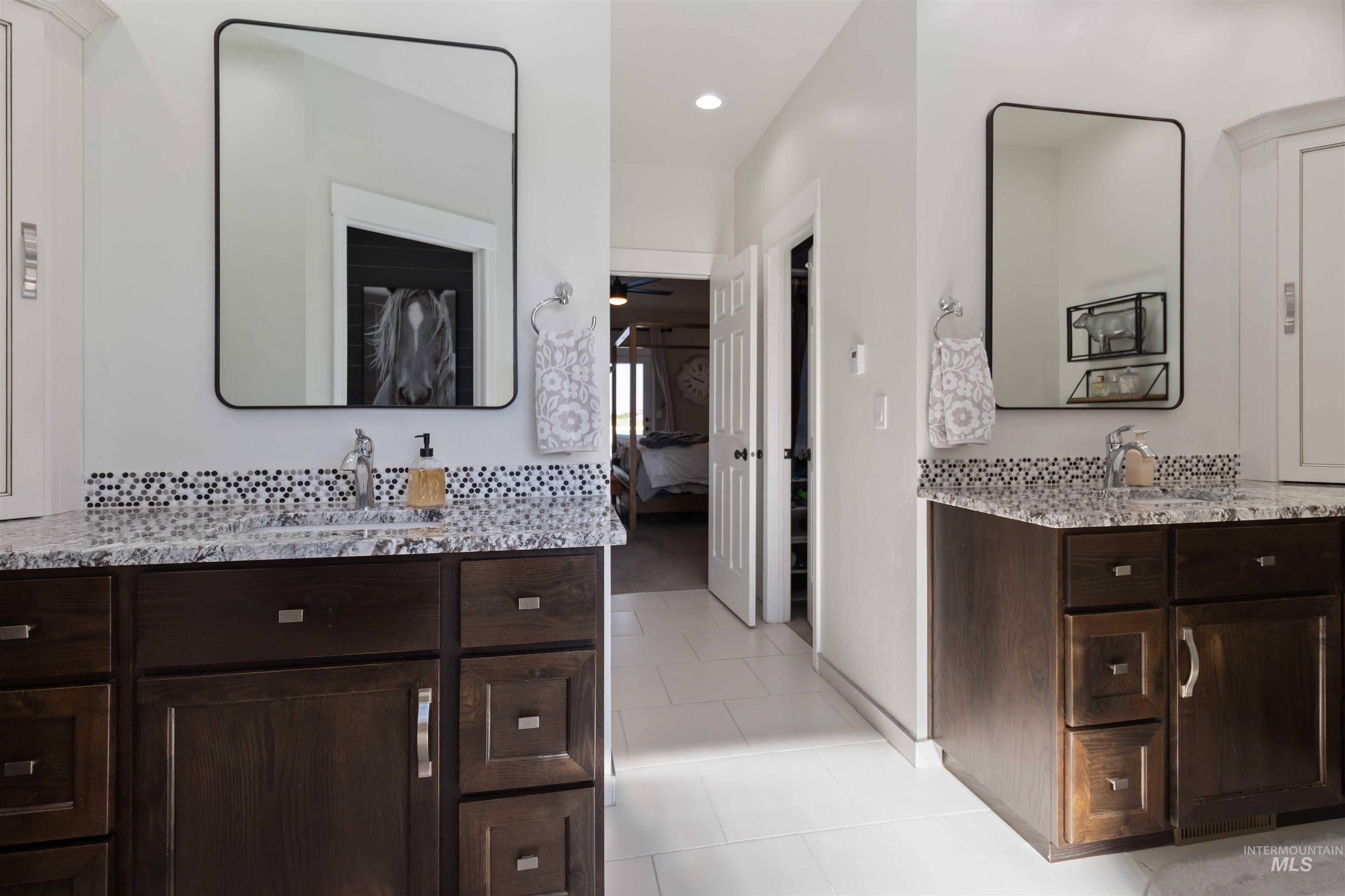 Ensuite bathroom featuring two vanities, light tile patterned floors, tasteful backsplash, and recessed lighting