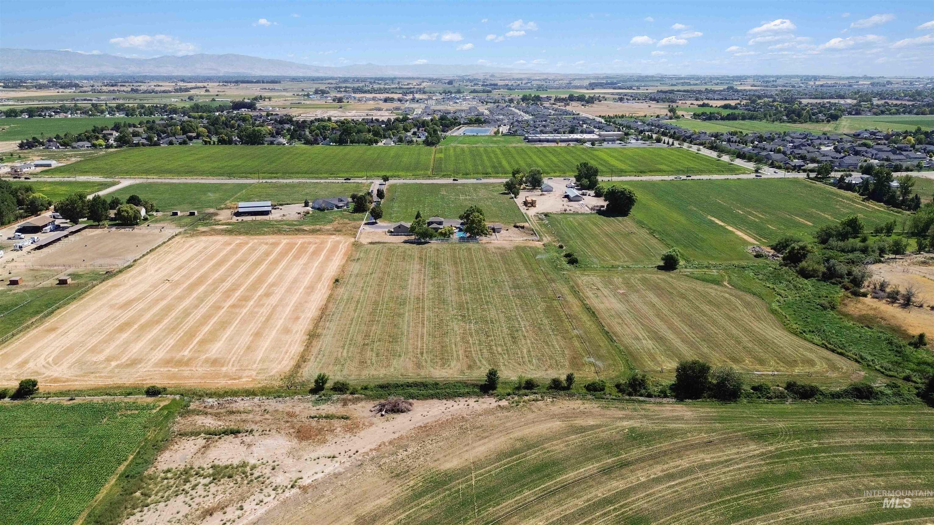 Aerial view of sparsely populated area featuring rows of crops and mountains