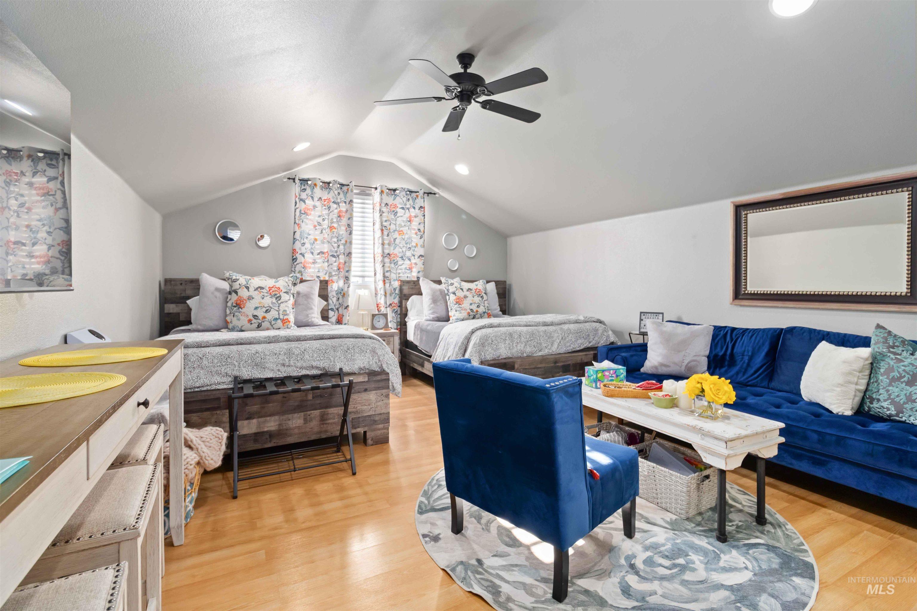 Bedroom featuring light wood-style floors, vaulted ceiling, and a ceiling fan