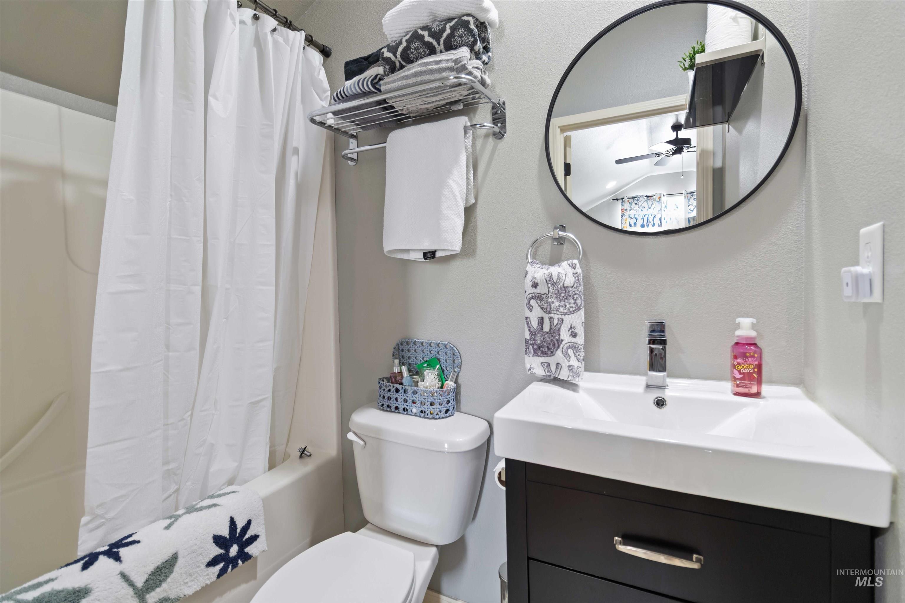 Bathroom with shower / bath combination with curtain, vanity, a textured wall, and ceiling fan