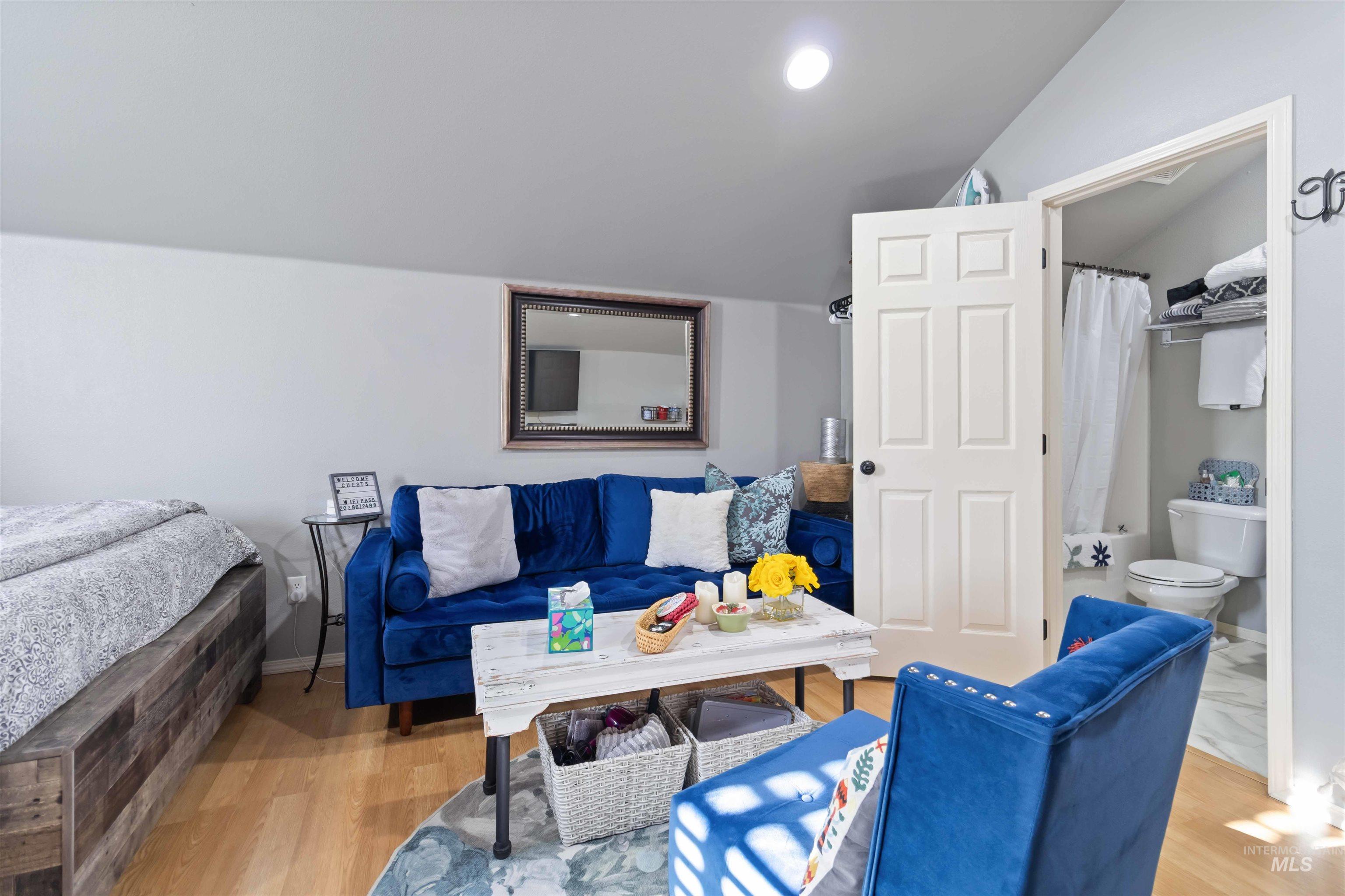 Bedroom featuring light wood-type flooring, vaulted ceiling, recessed lighting, and connected bathroom
