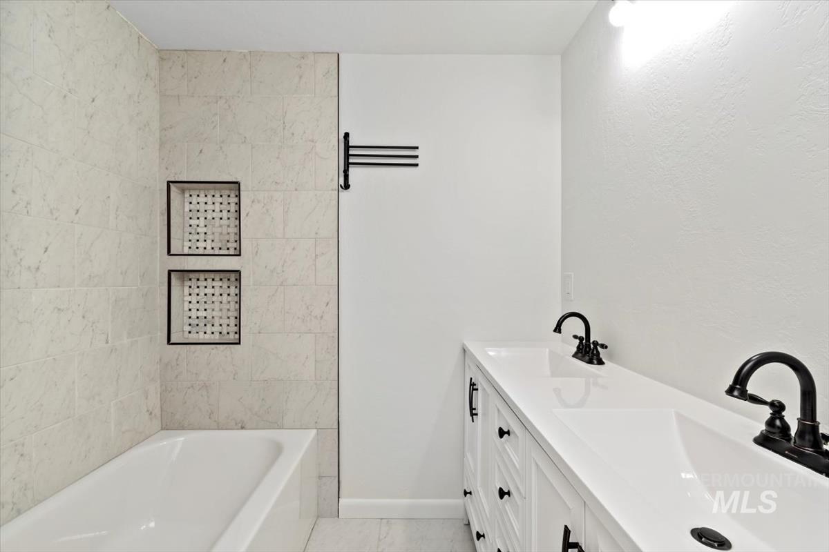Full bath with double vanity, light tile patterned floors, and shower / bath combination