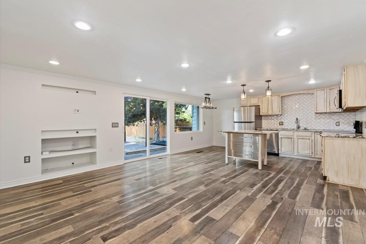Kitchen with decorative light fixtures, dark wood-style flooring, a kitchen island, recessed lighting, and light stone counters