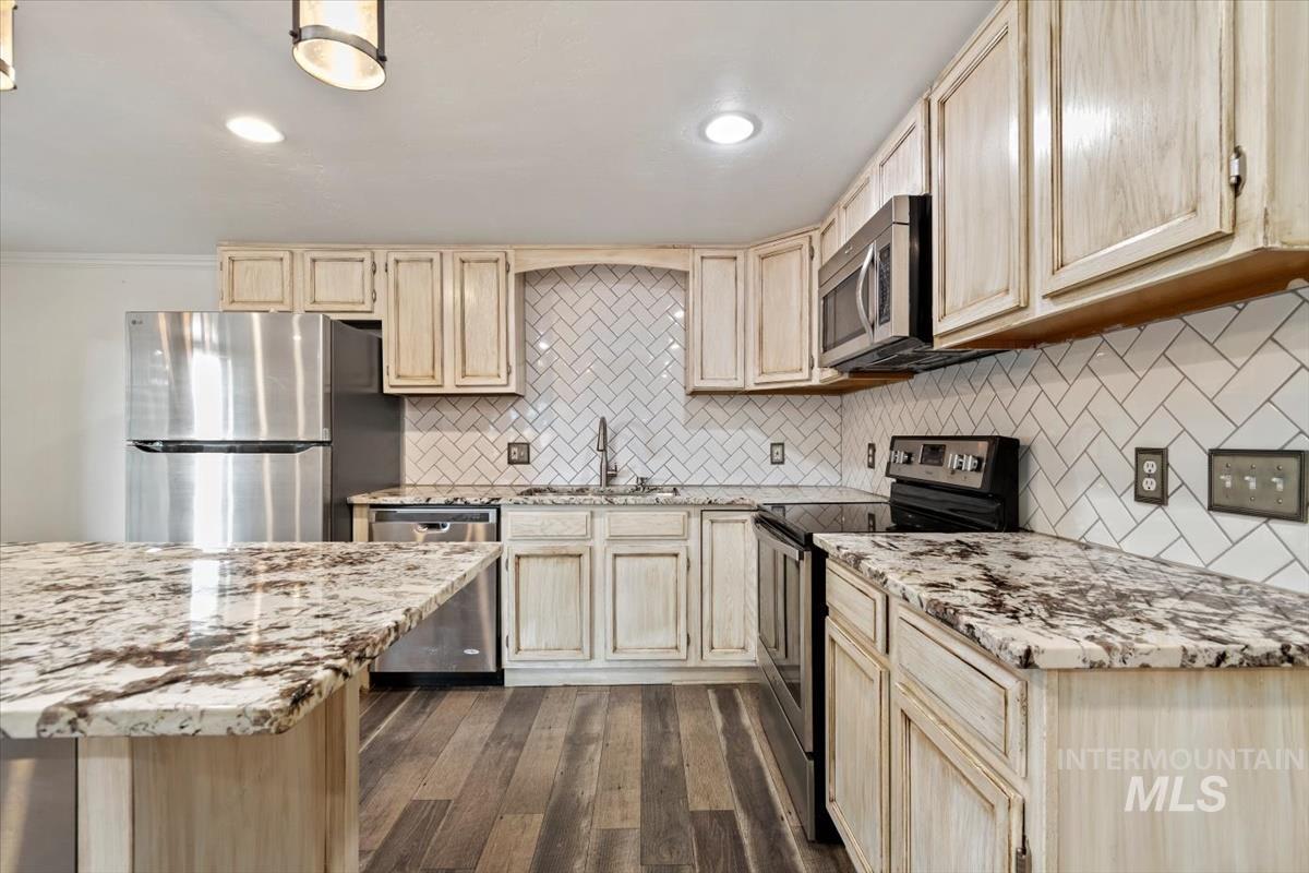 Kitchen featuring appliances with stainless steel finishes, dark wood finished floors, light stone countertops, light brown cabinetry, and recessed lighting