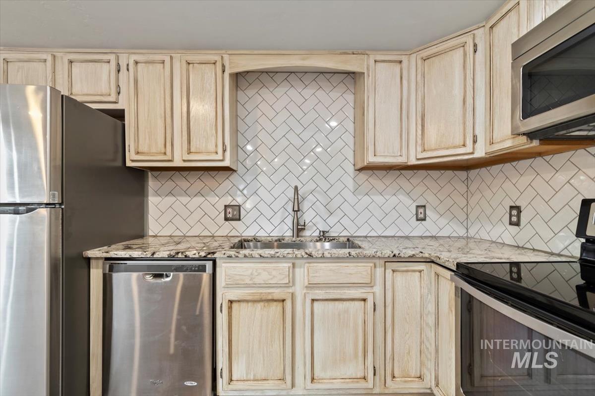 Kitchen with appliances with stainless steel finishes, light brown cabinets, and decorative backsplash