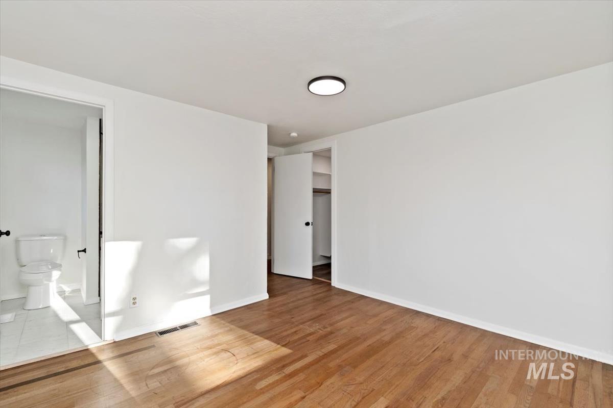 Unfurnished bedroom with wood finished floors and baseboards