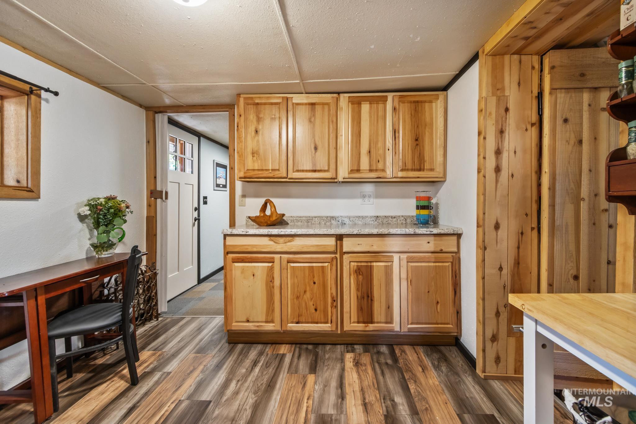Kitchen featuring dark wood-style flooring and light stone counters