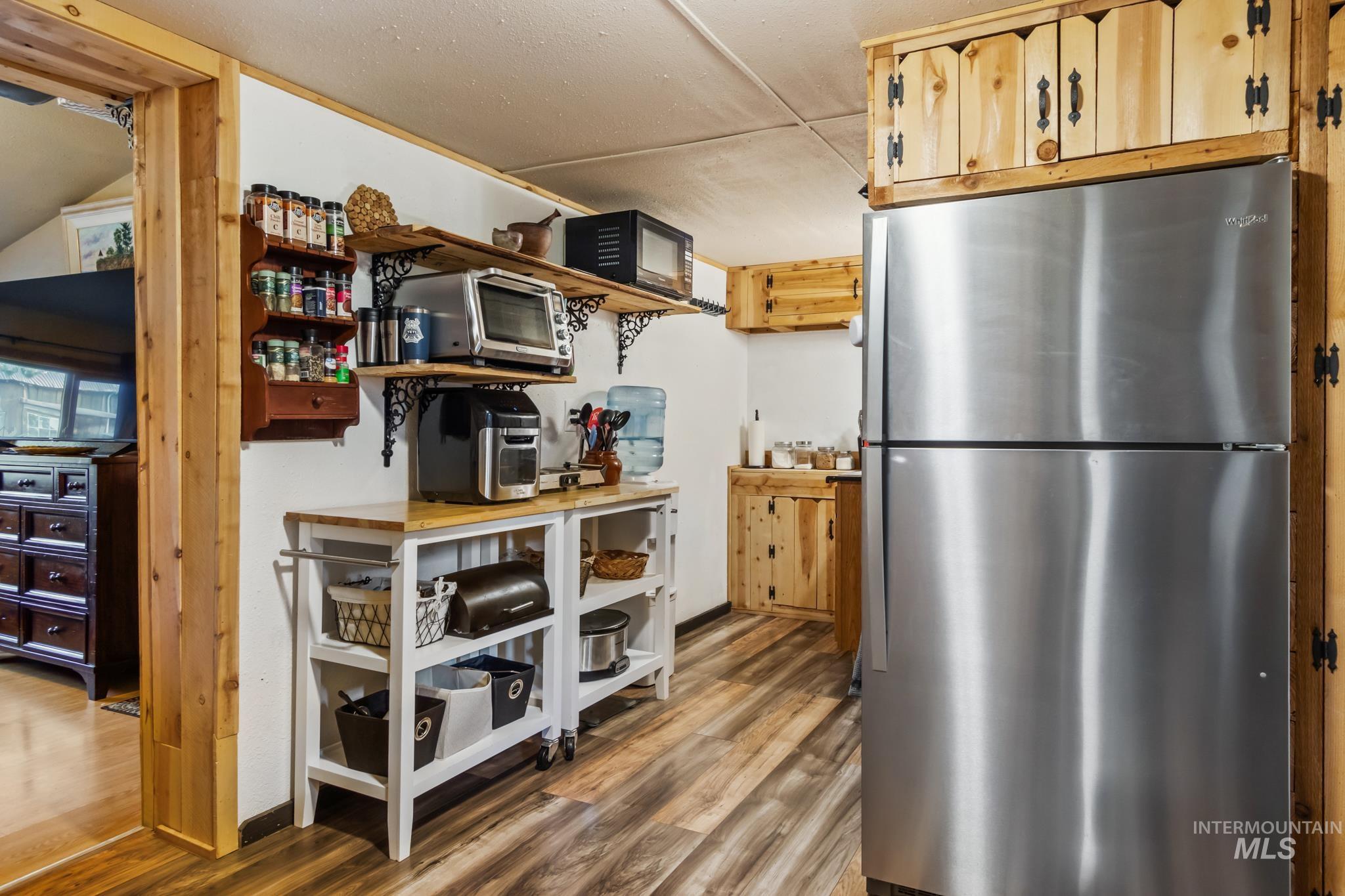 Kitchen with freestanding refrigerator, light wood-style flooring, and open shelves