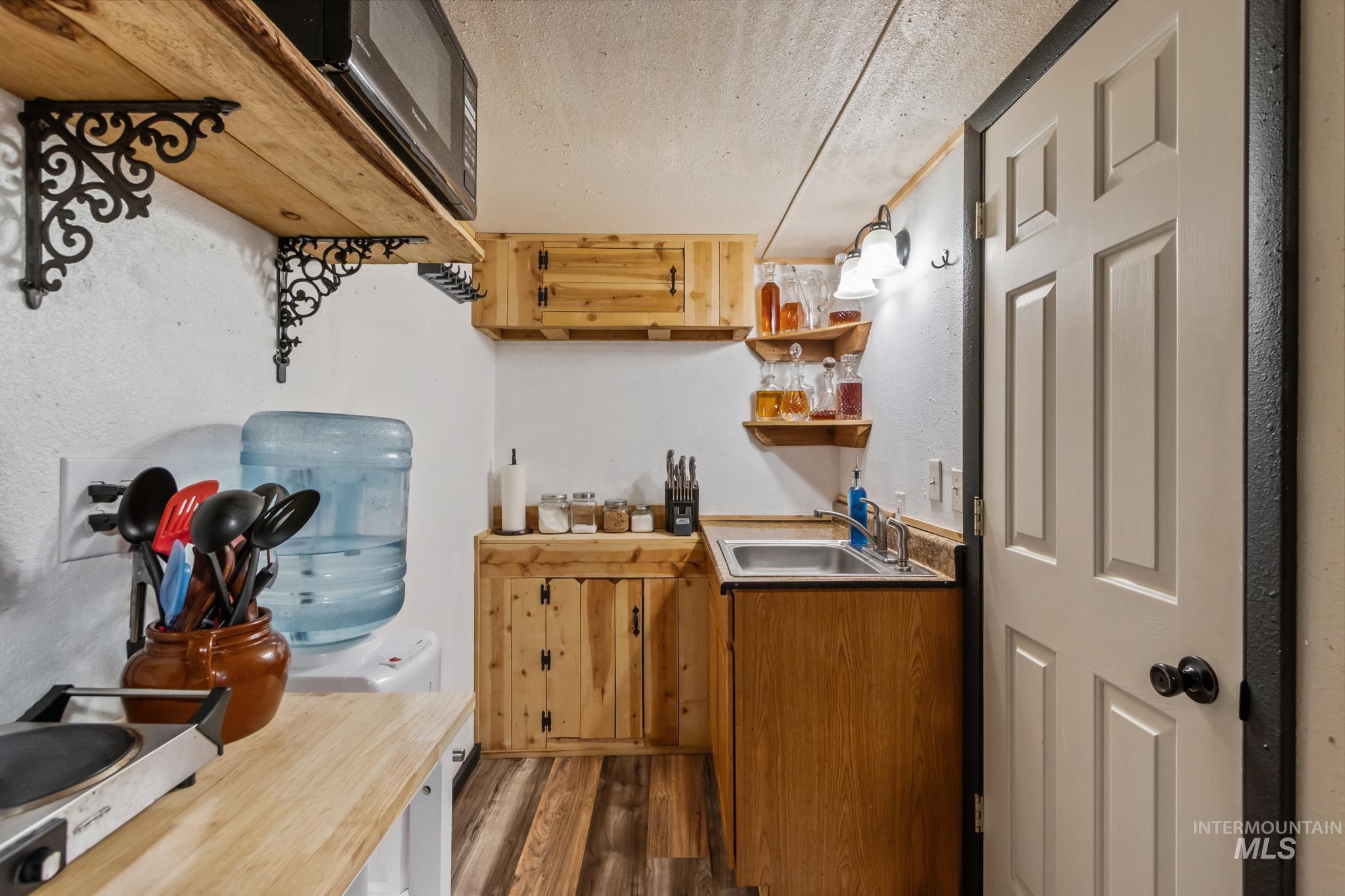 Bar featuring dark wood-style floors, butcher block countertops, a textured wall, open shelves, and a textured ceiling