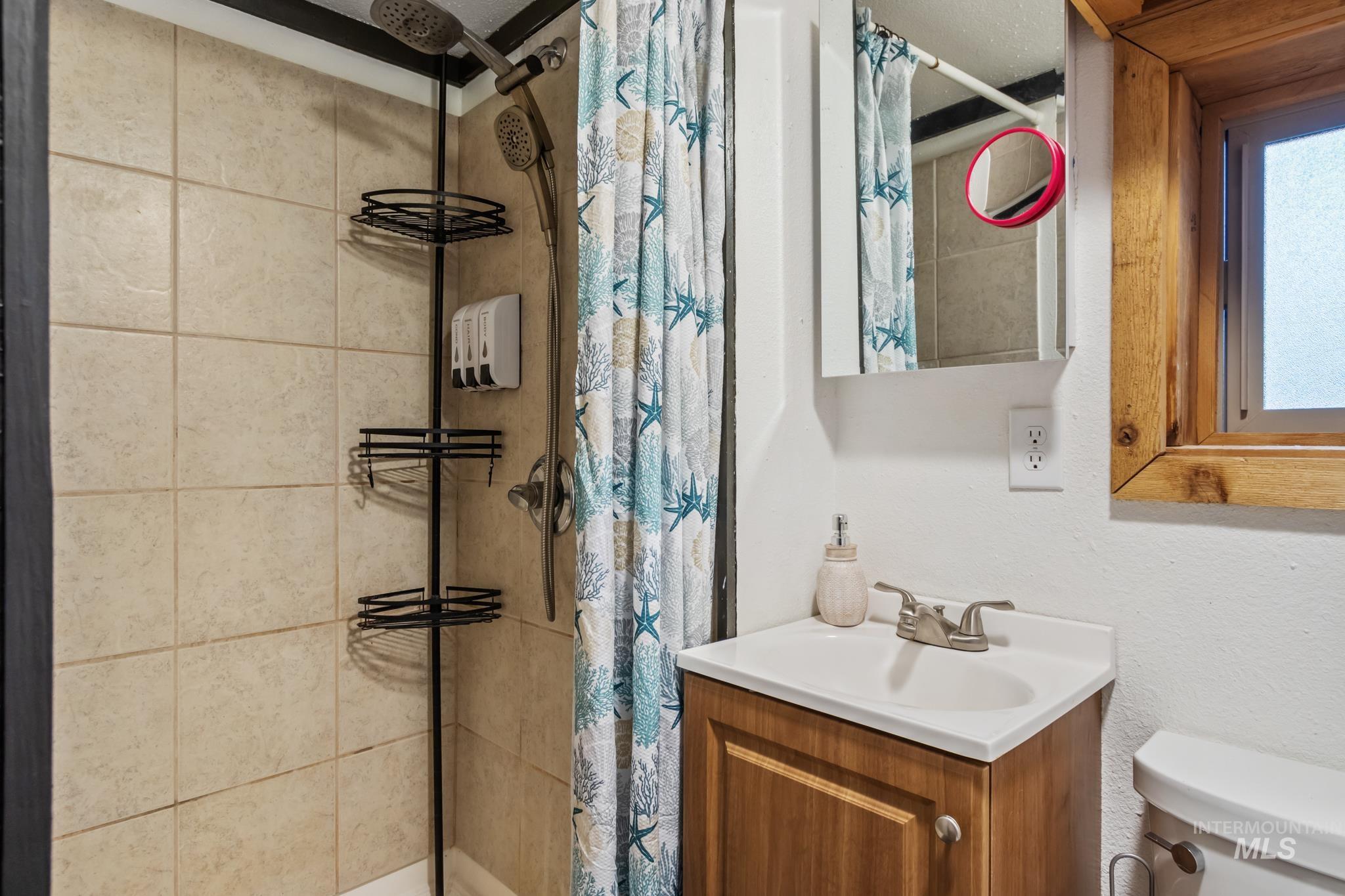 Bathroom featuring vanity, a tile shower, and a textured wall