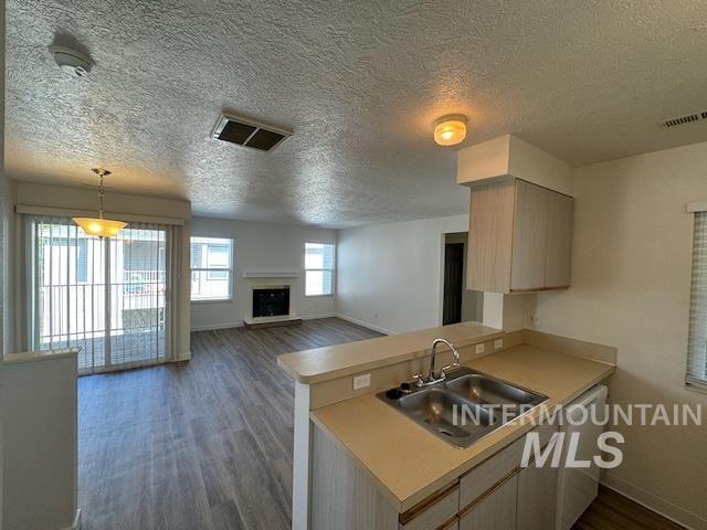 Kitchen featuring light countertops, dark wood-style floors, open floor plan, a textured ceiling, and a fireplace