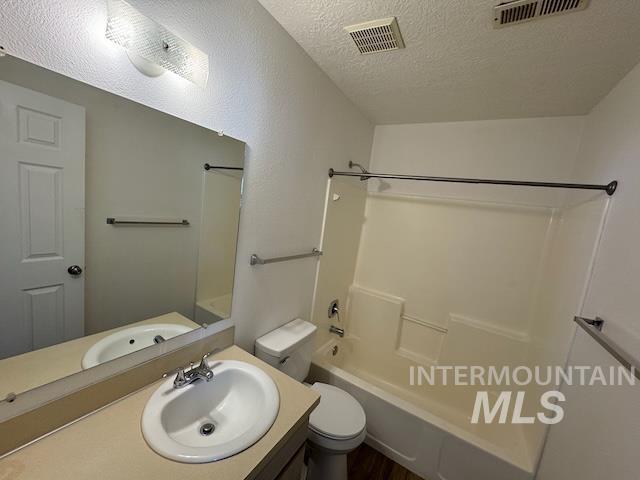 Bathroom featuring  shower combination, a textured ceiling, vanity, and dark wood-style flooring