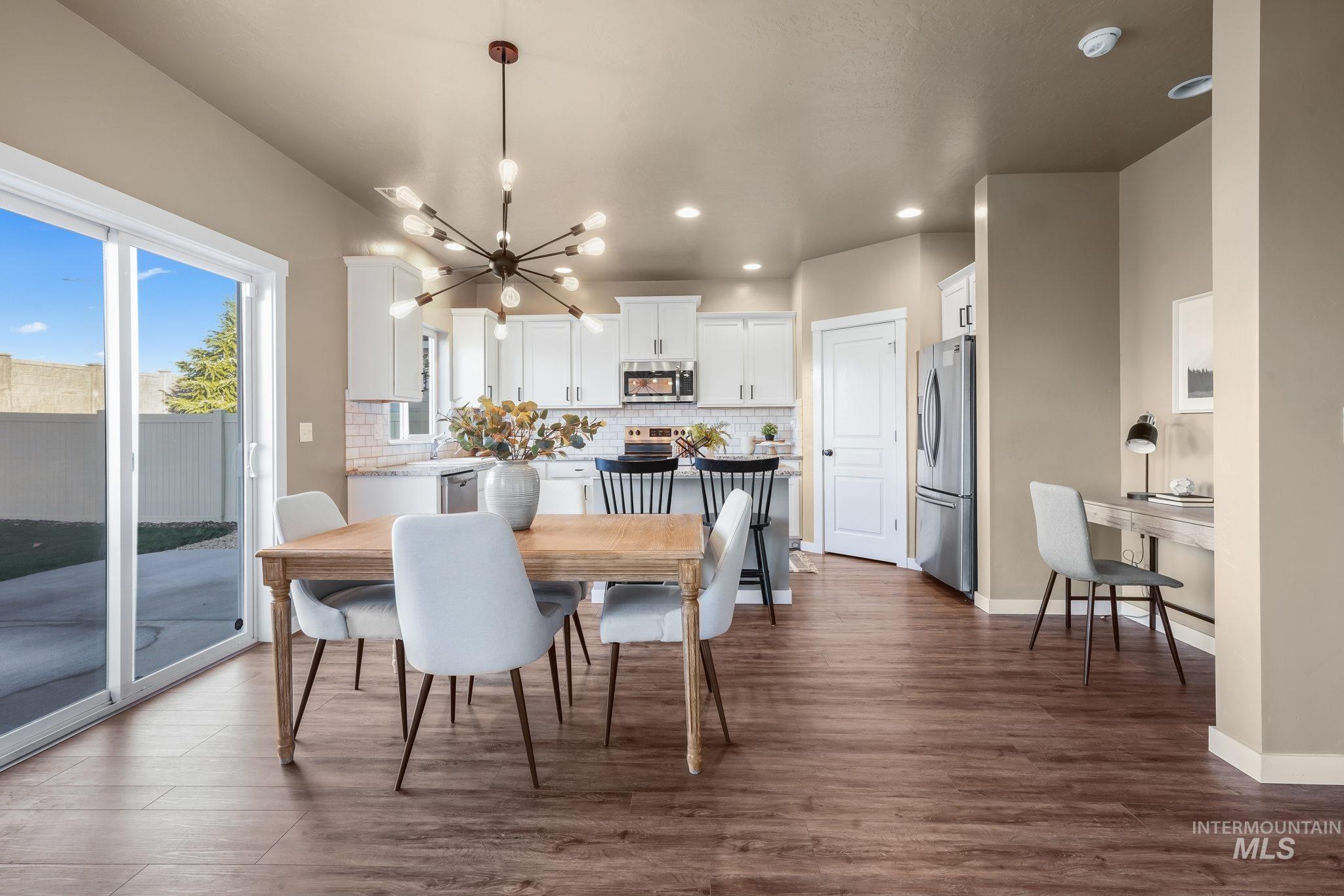 Dining area with a chandelier, dark wood-style floors, and recessed lighting