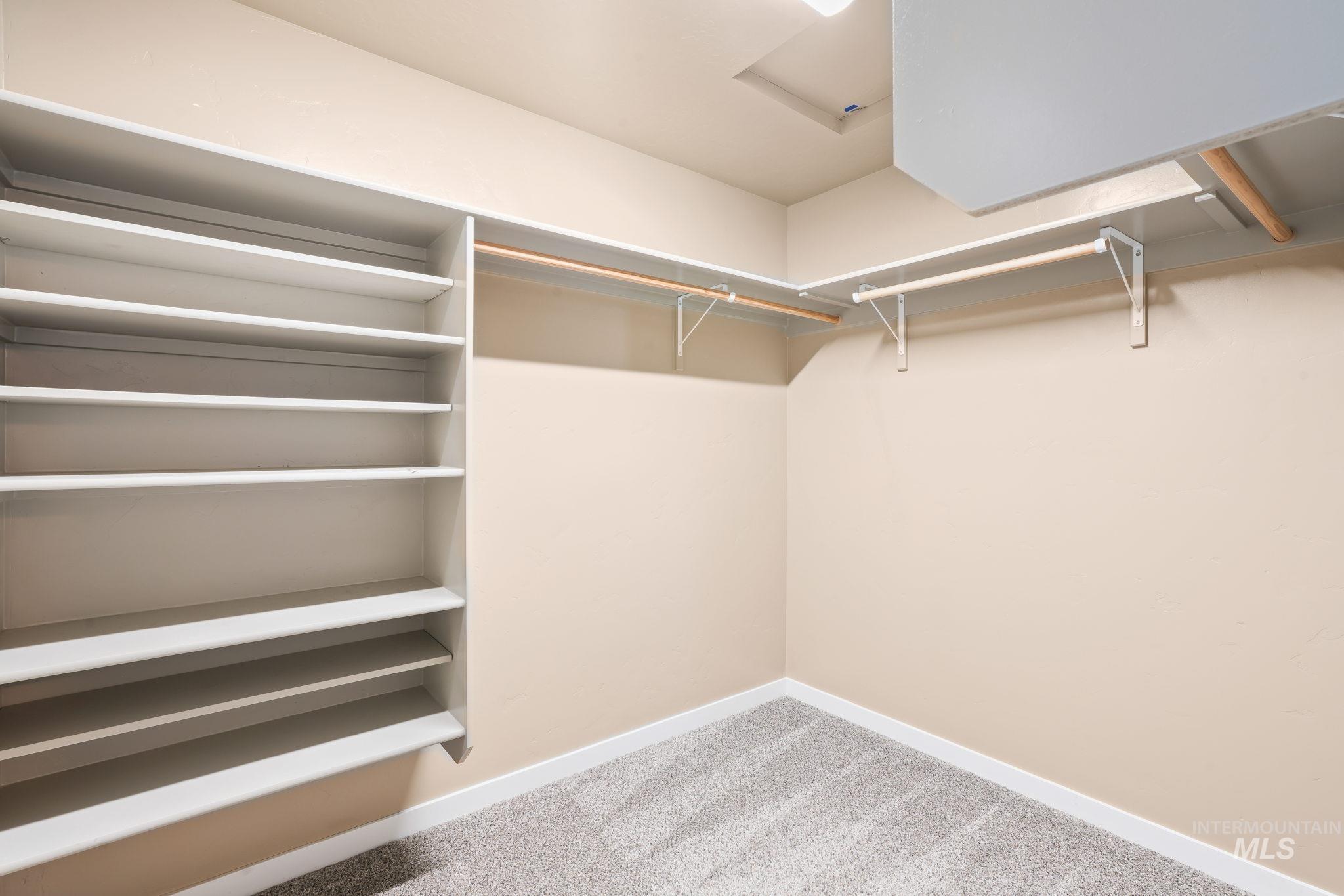 Walk in closet with light carpet and attic access