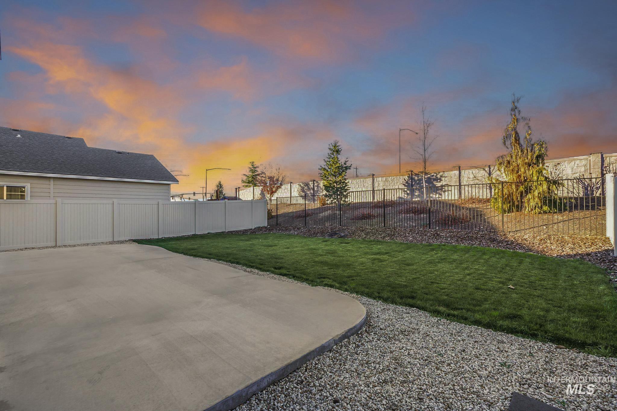Yard at dusk with a fenced backyard and a patio area