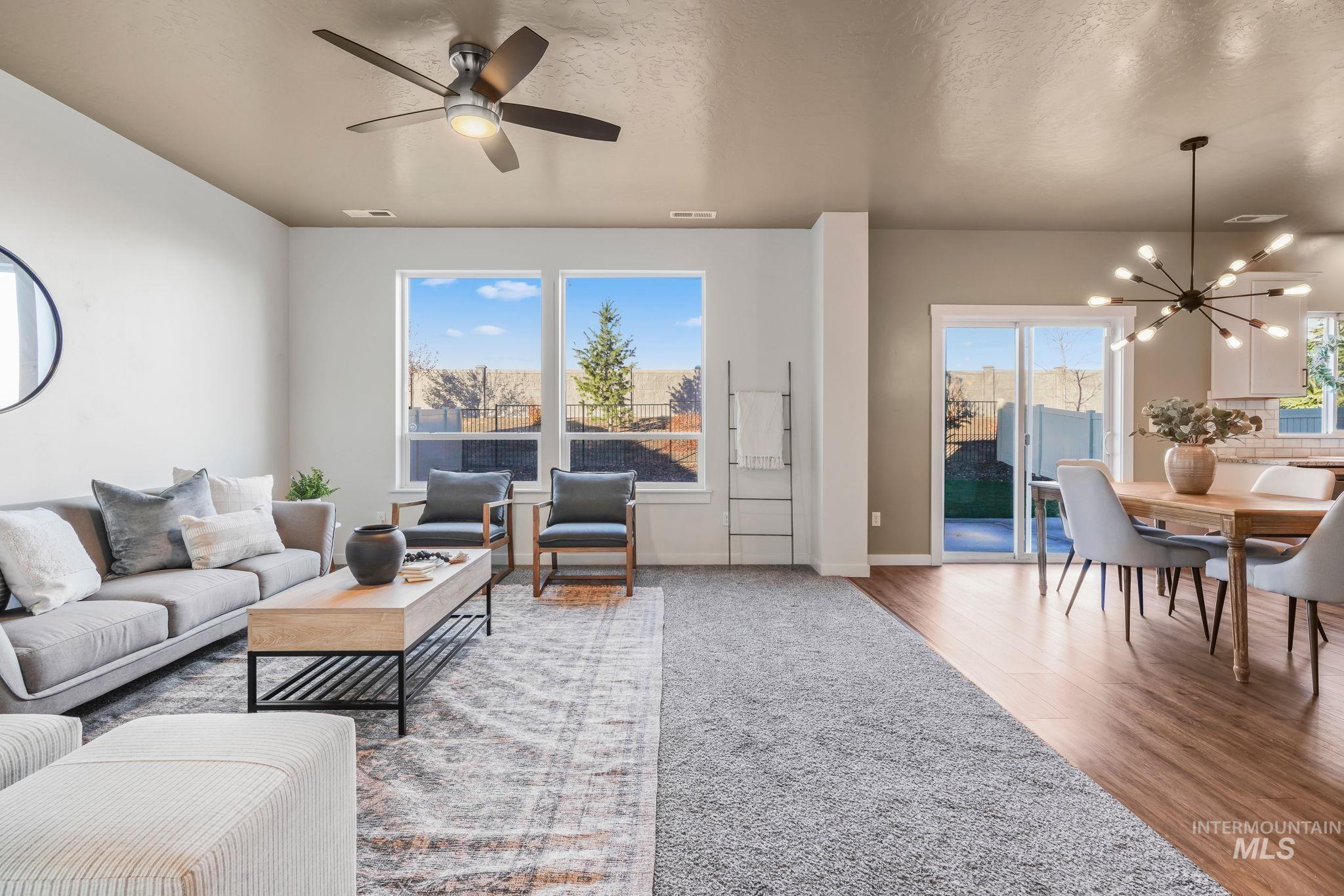 Living area with a chandelier, a textured ceiling, light wood finished floors, and a ceiling fan
