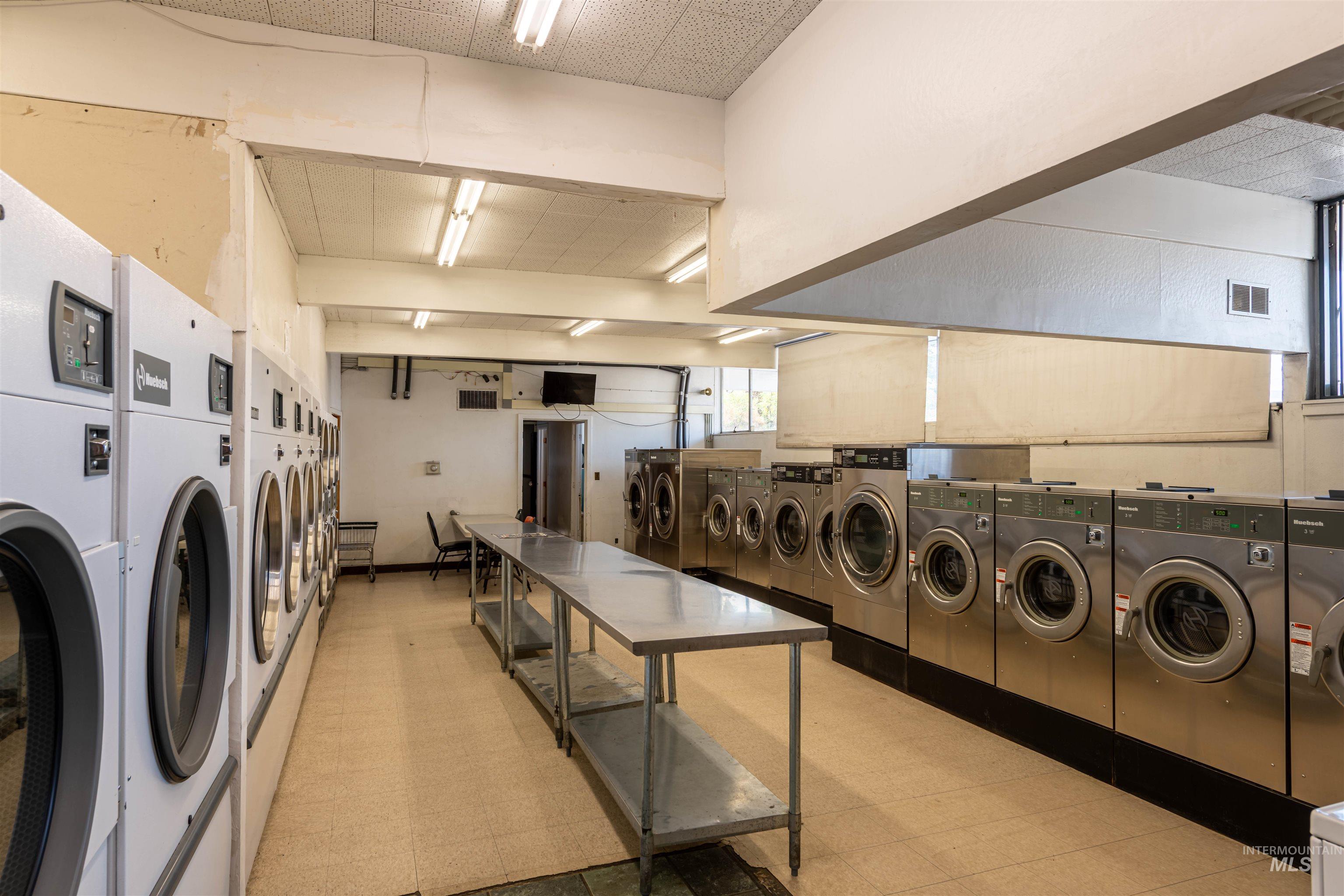 Shared laundry room with light floors and separate washer and dryer