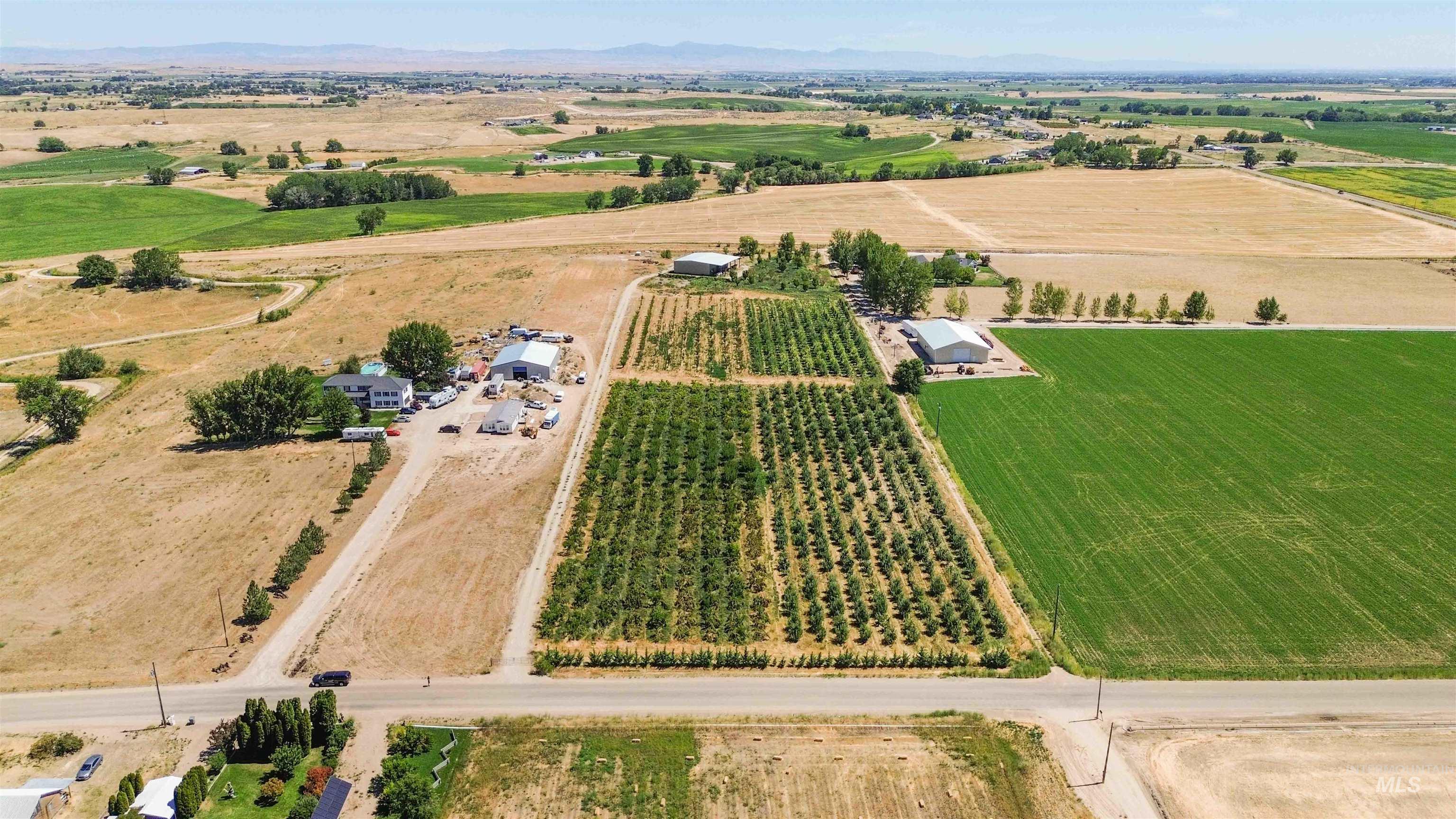 Aerial view of property and surrounding area featuring rural landscape and a mountainous background
