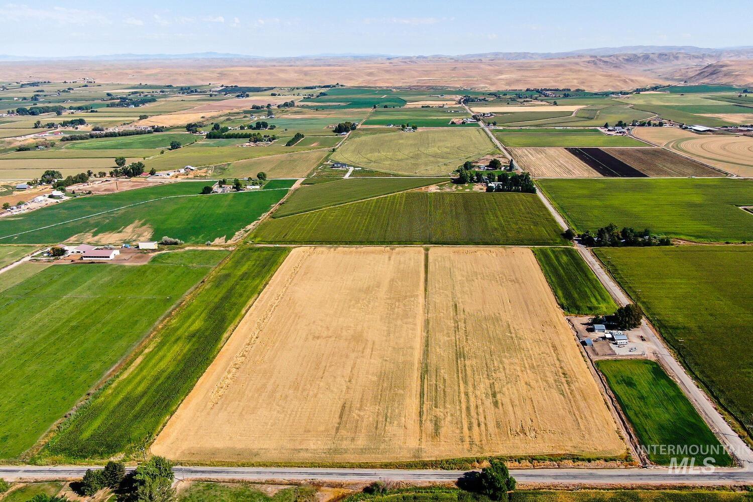 Aerial overview of property's location featuring rural landscape, rows of crops, and a mountain backdrop