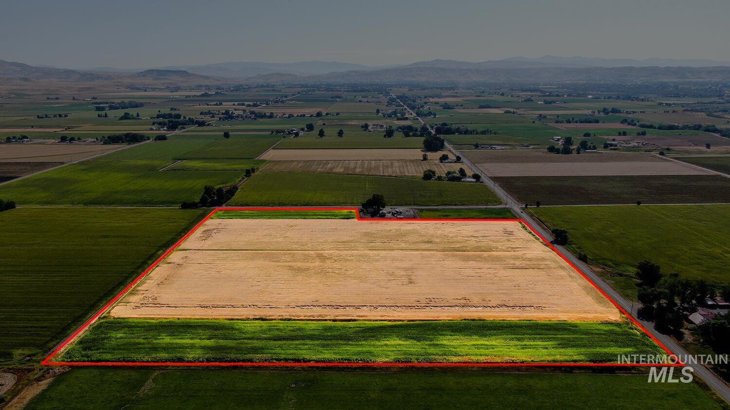 Overview of rural landscape featuring rows of crops, property parcel outlined, and mountains