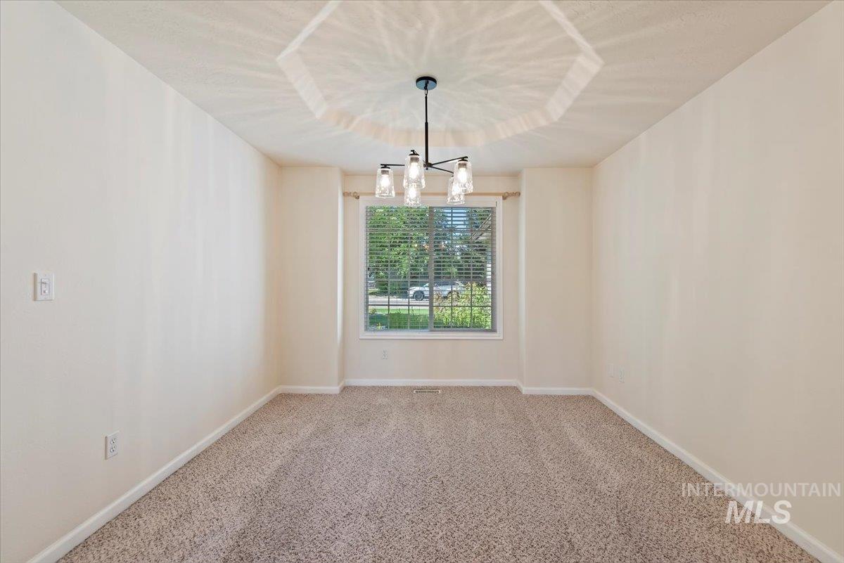 Carpeted spare room with baseboards and a chandelier