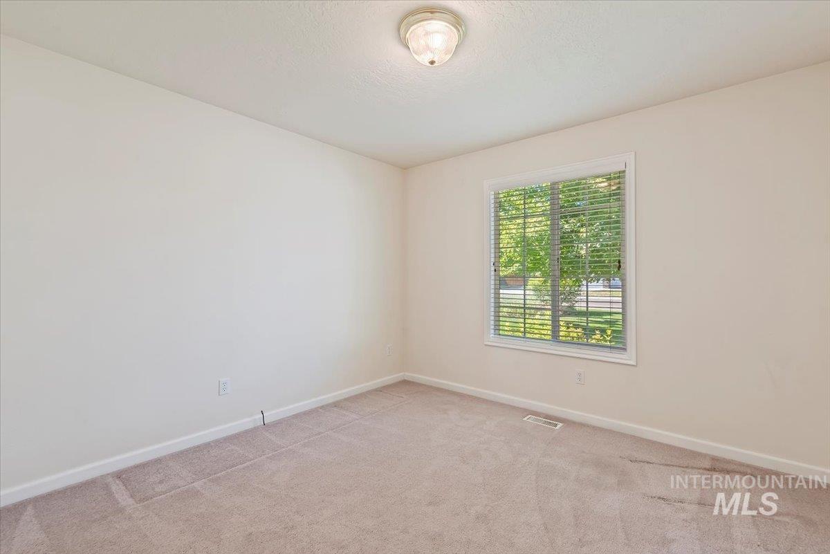 Empty room featuring baseboards and light carpet