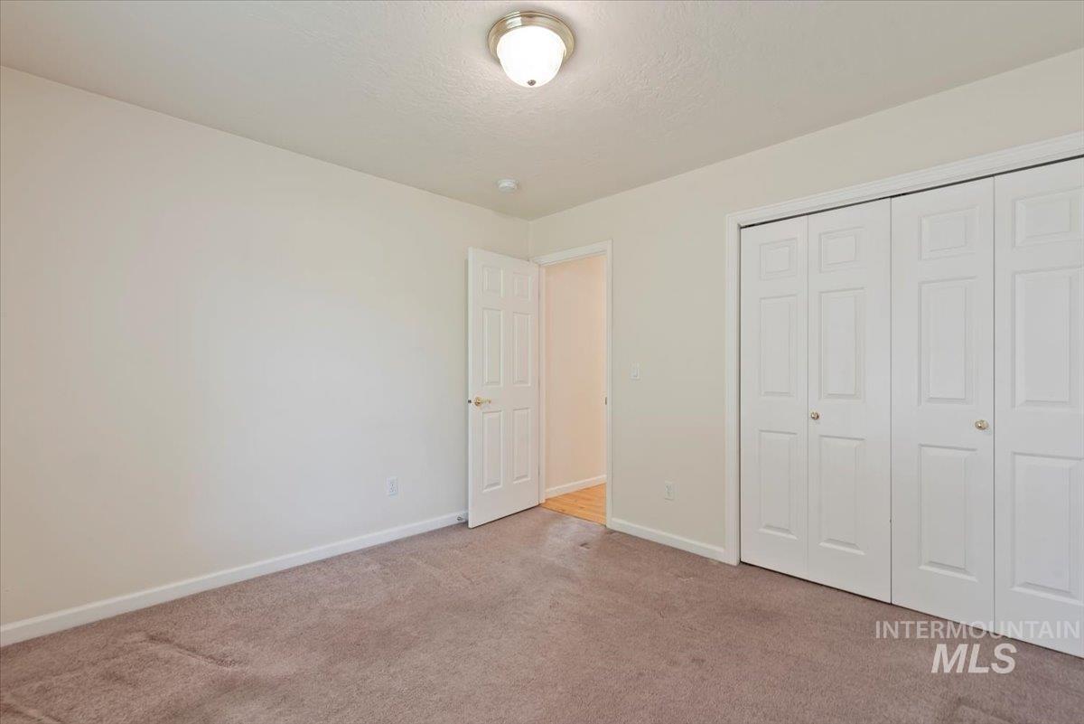 Unfurnished bedroom with light carpet, a closet, and a textured ceiling