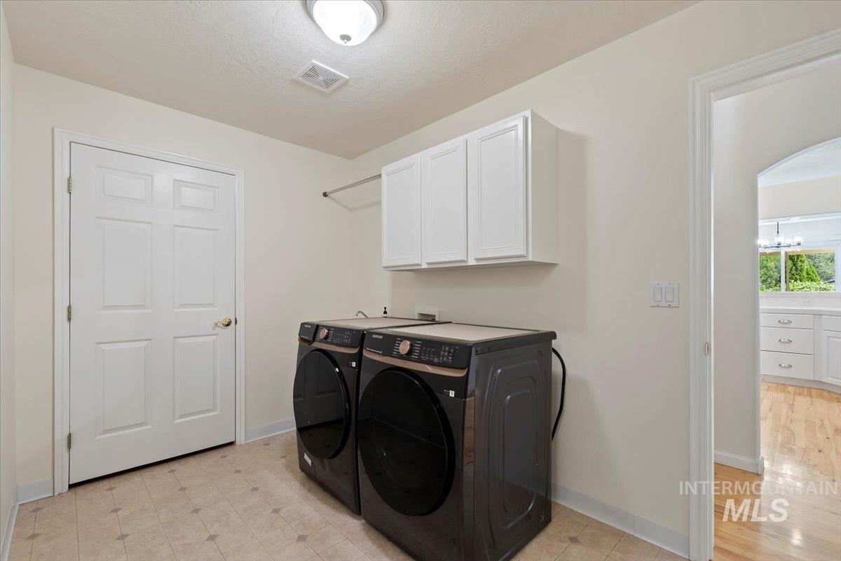 Laundry room featuring separate washer and dryer, a textured ceiling, and cabinet space