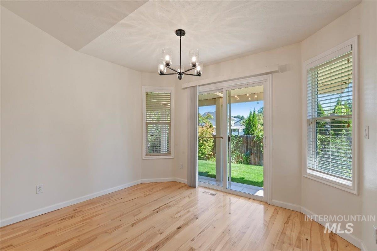 Unfurnished dining area featuring light wood-style floors, a chandelier, and plenty of natural light