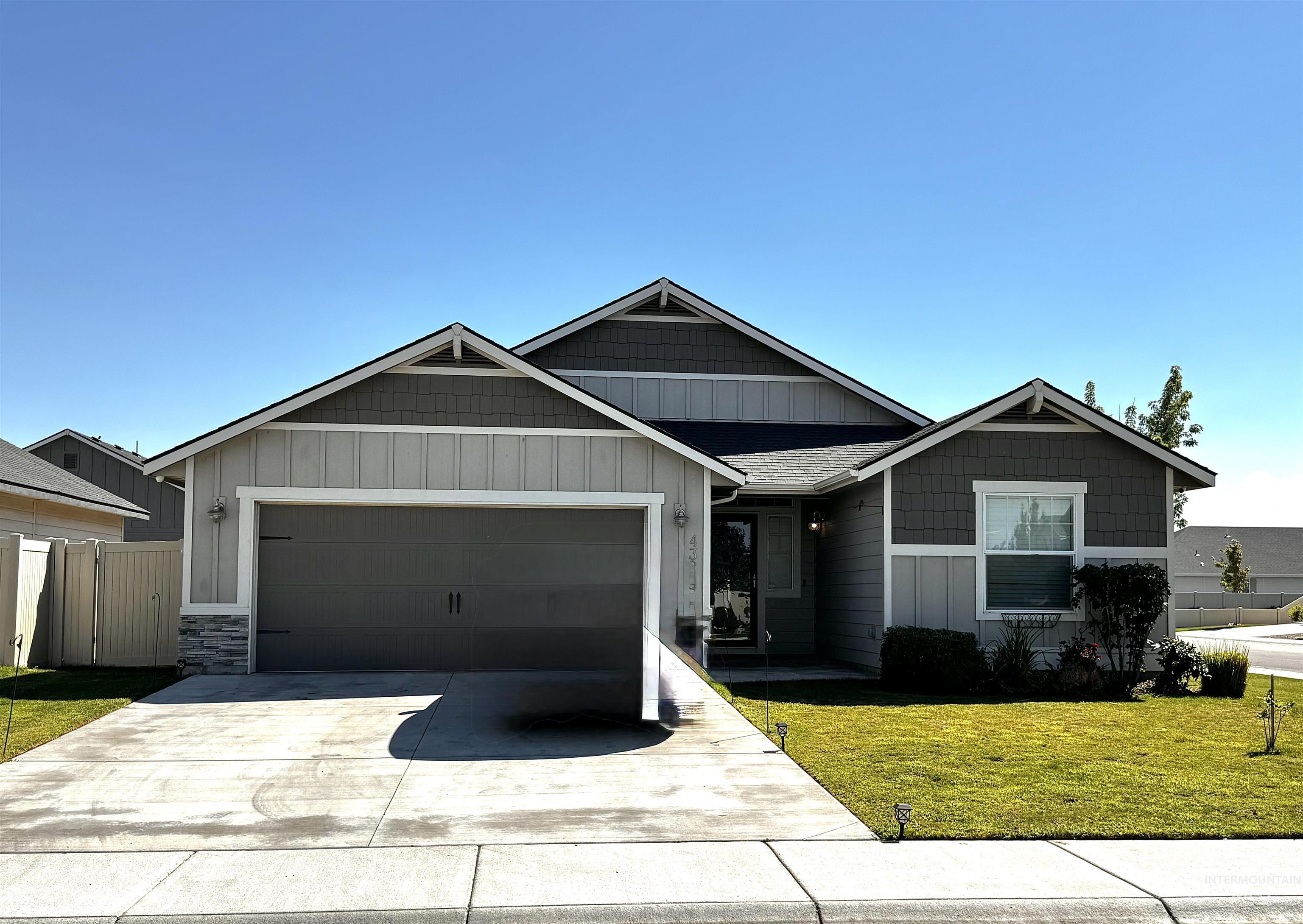 View of front facade featuring board and batten siding, stone siding, an attached garage, and driveway