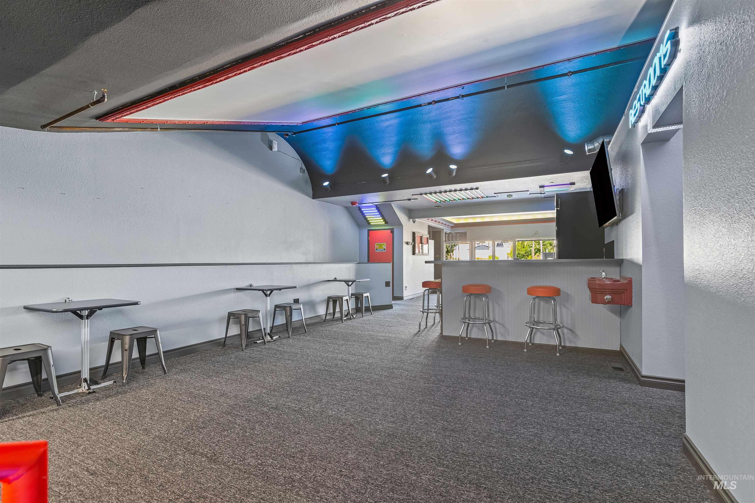Cinema room featuring dark colored carpet, a community bar, and lofted ceiling