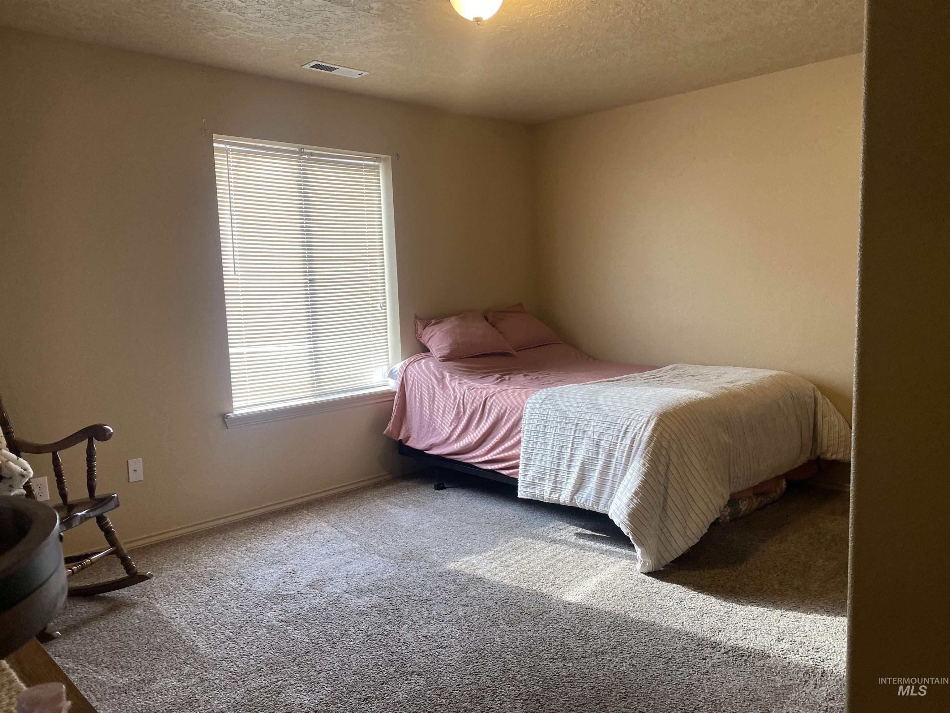 Carpeted bedroom featuring a textured ceiling and baseboards