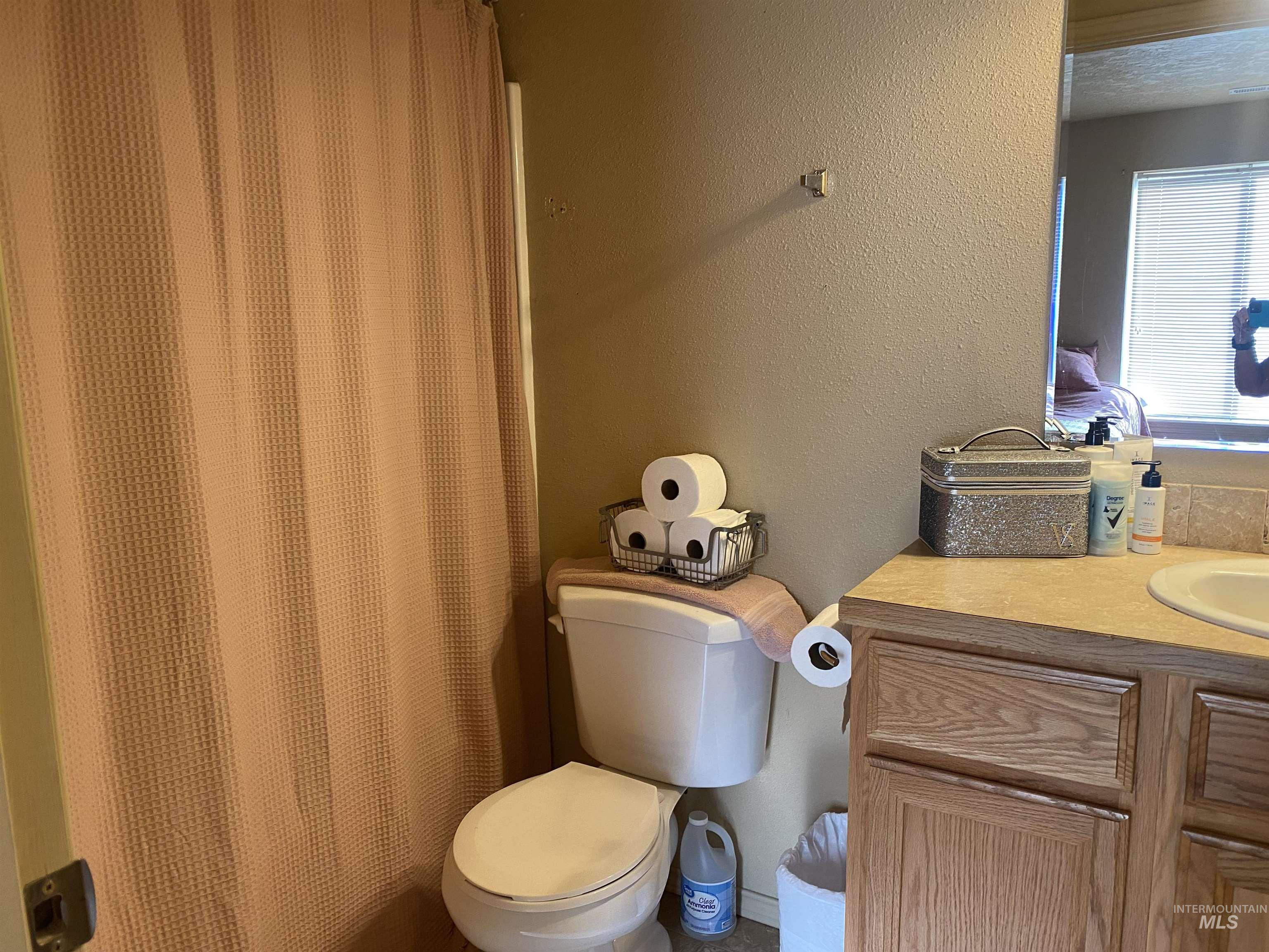Bathroom with a textured wall, vanity, and curtained shower